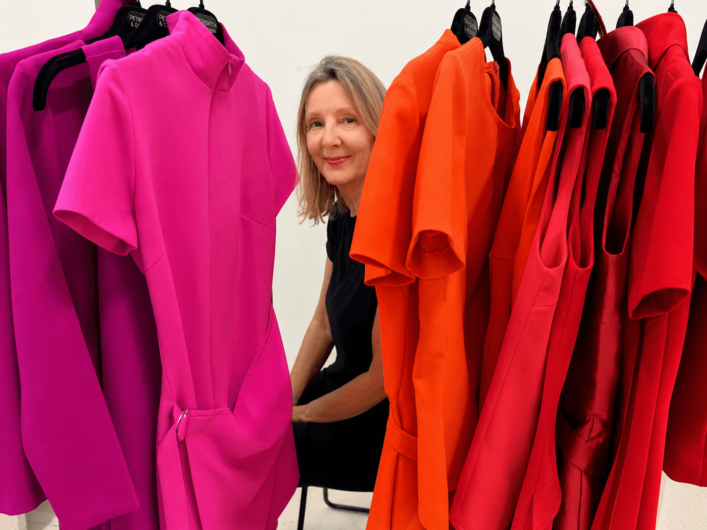 Eva Robinson parmi les robes fuchsia, orange et rouges